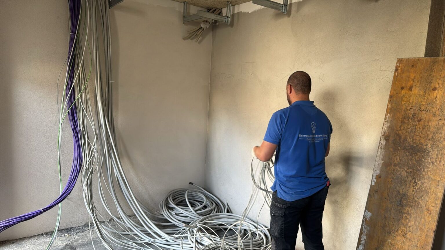 Elektriker verlegt Kabel an einer Wand