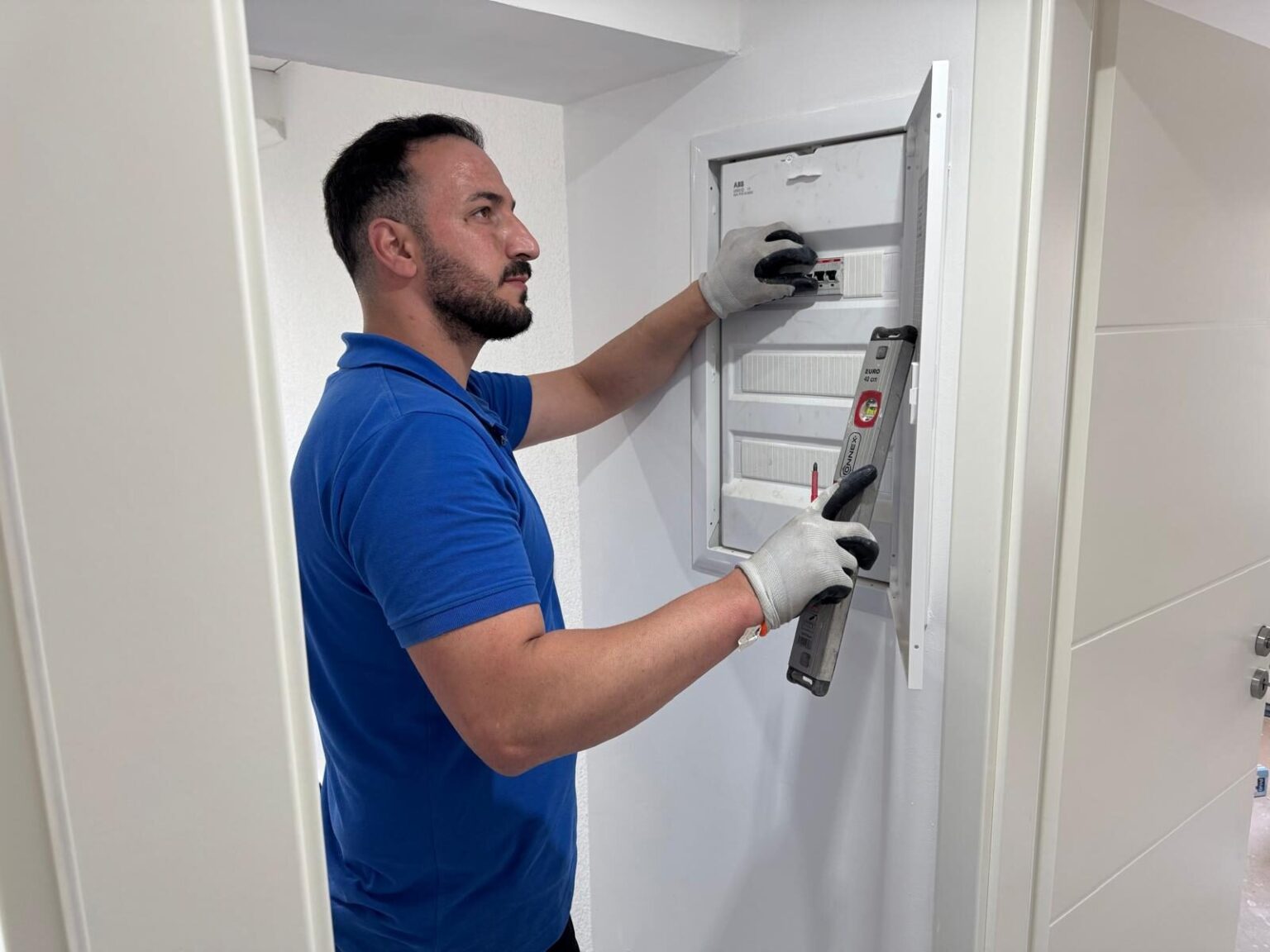 Elektriker überprüft Stromkasten mit Wasserwaage.