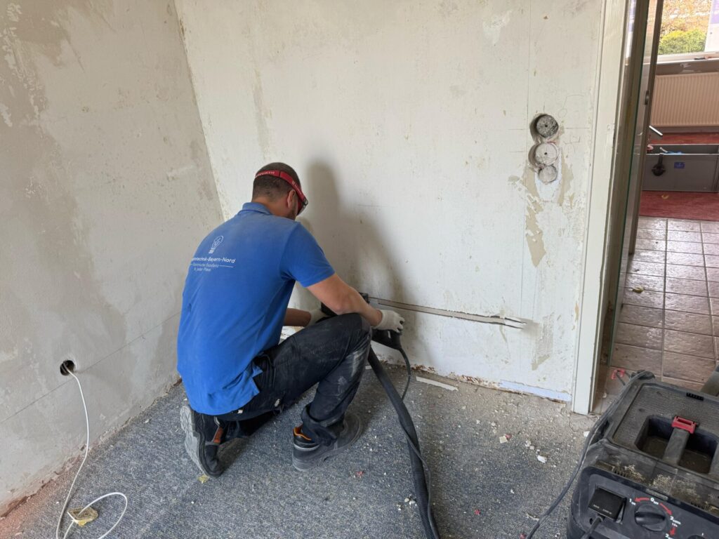 Handwerker arbeitet an elektrischer Installation in Wand