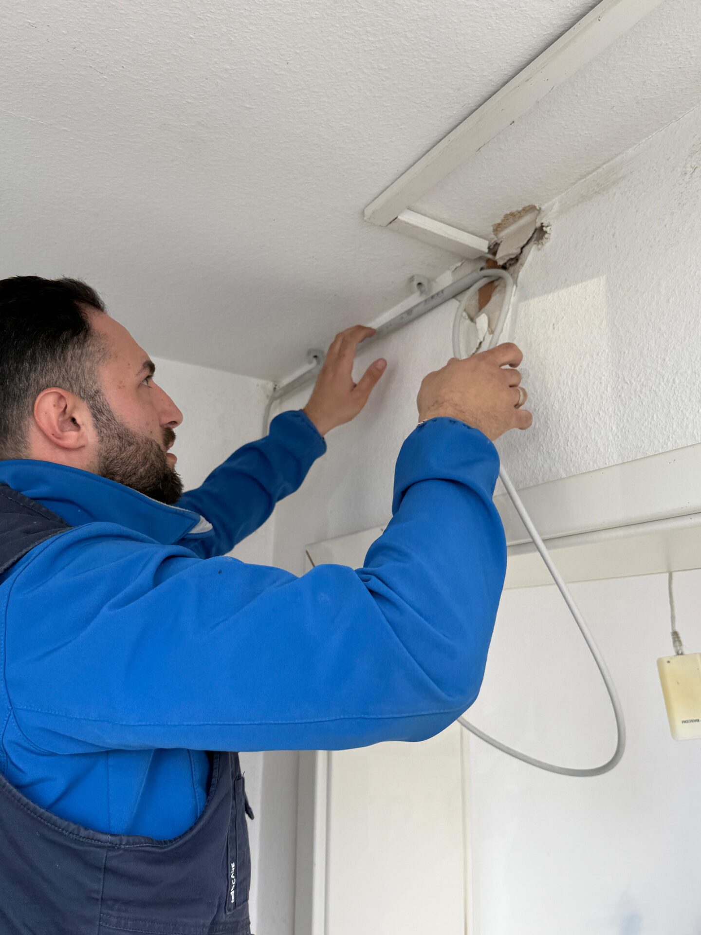 Elektriker verlegt eine neue Leitung entlang der Zimmerdecke
