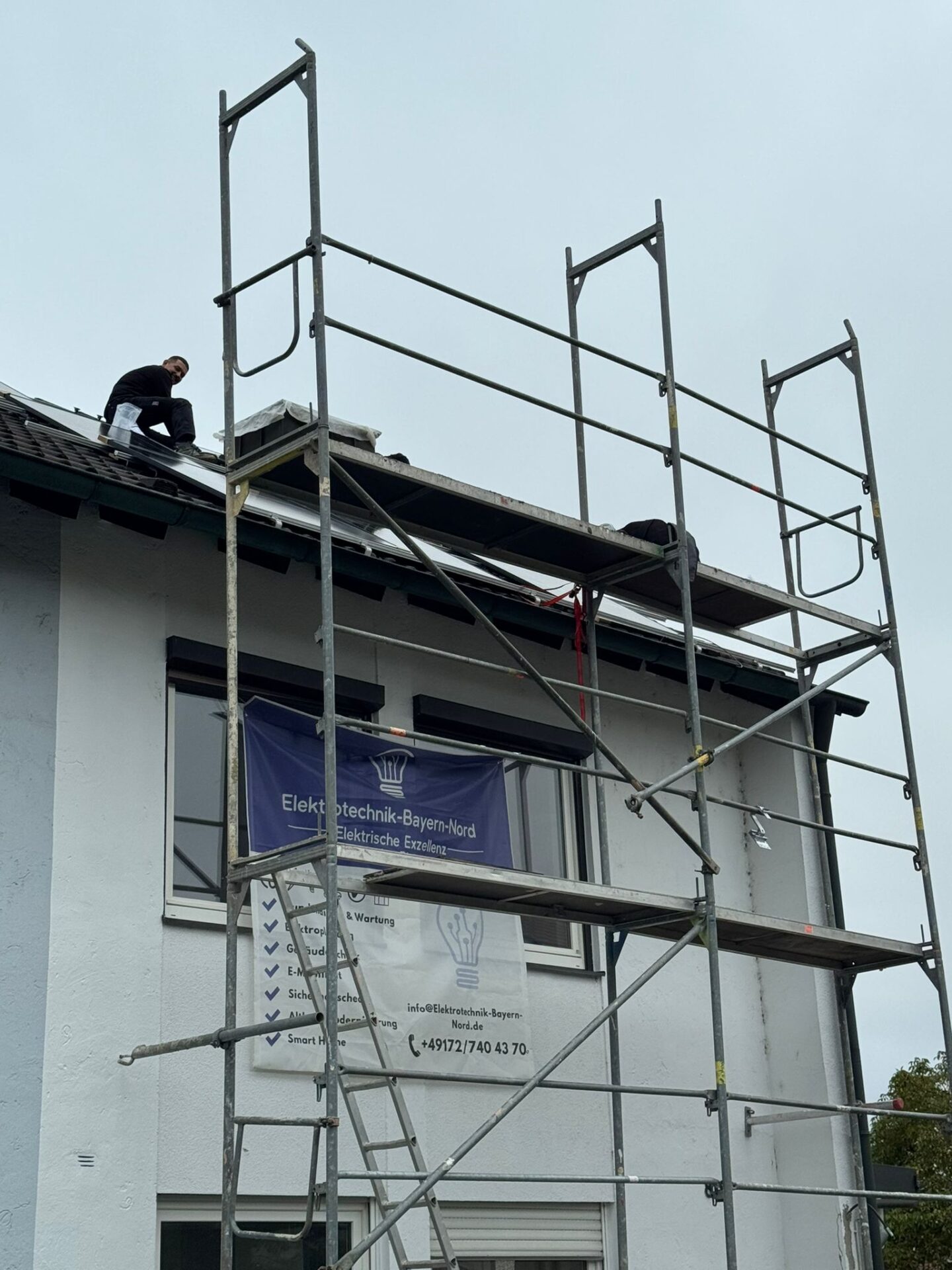 Mann arbeitet auf Dach mit Gerüst