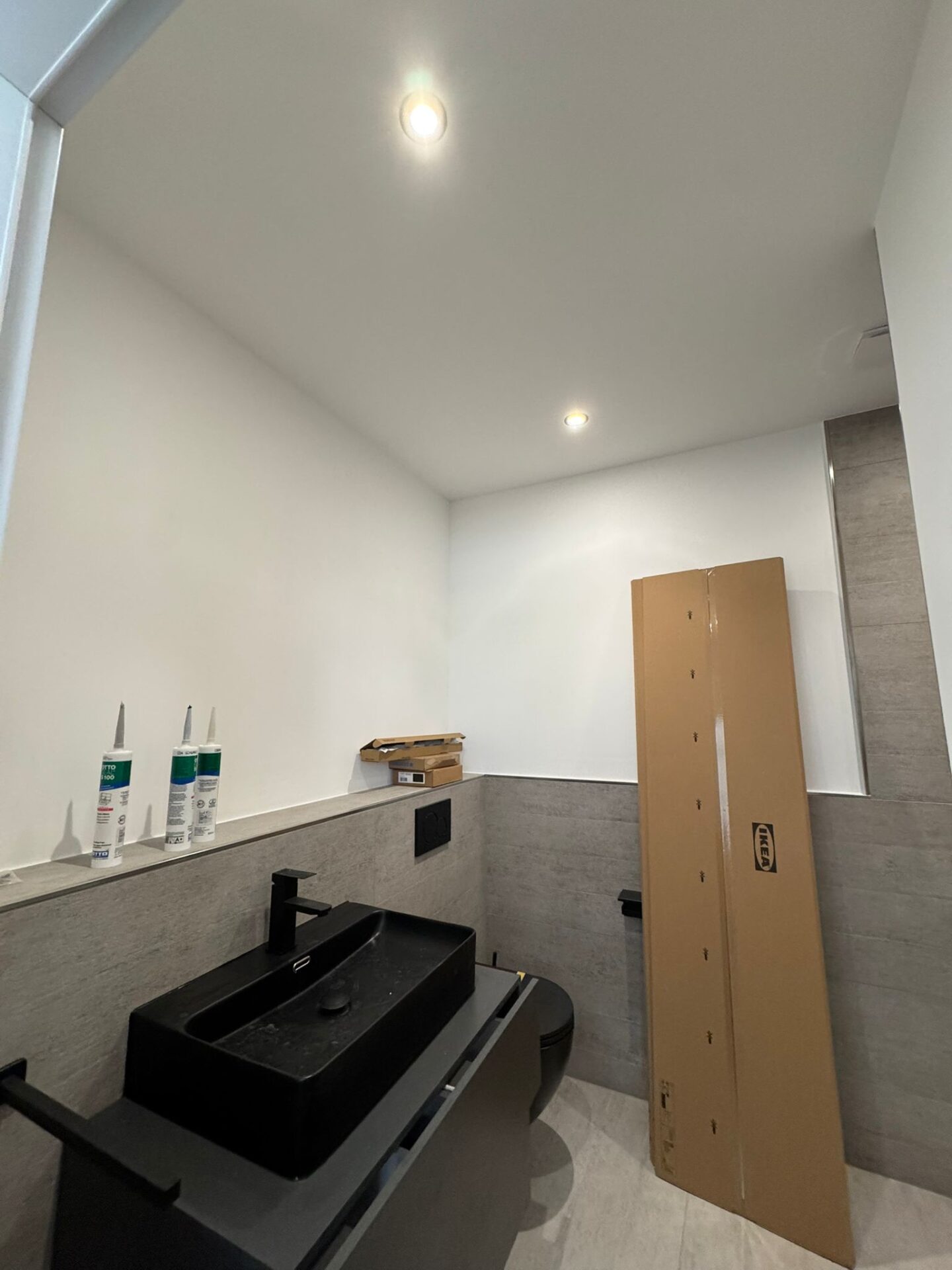 Modernes Badezimmer mit schwarzem Waschbecken und Karton.