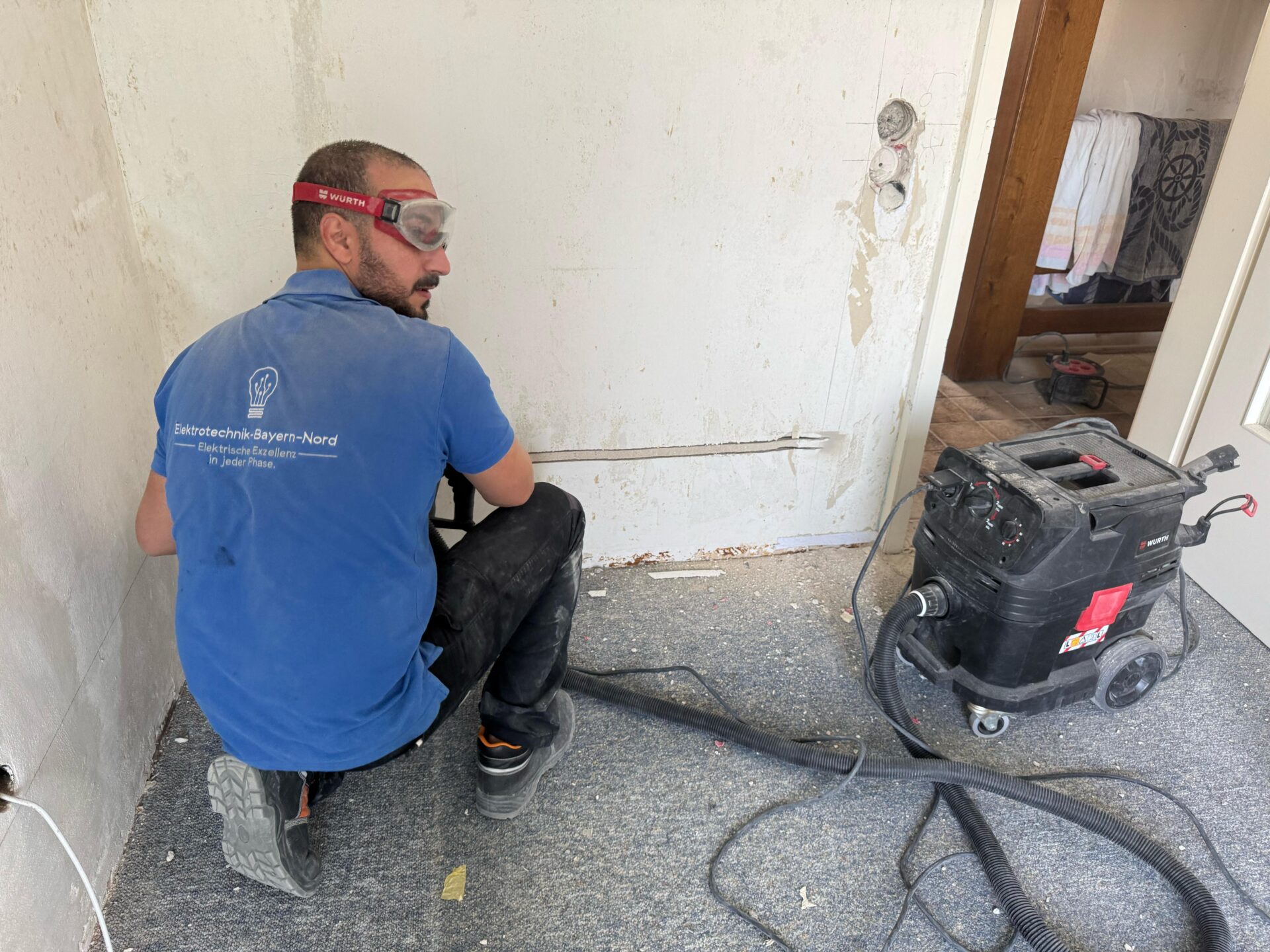 Elektriker mit Schutzbrille schlitzt eine Wand für neue Kabel