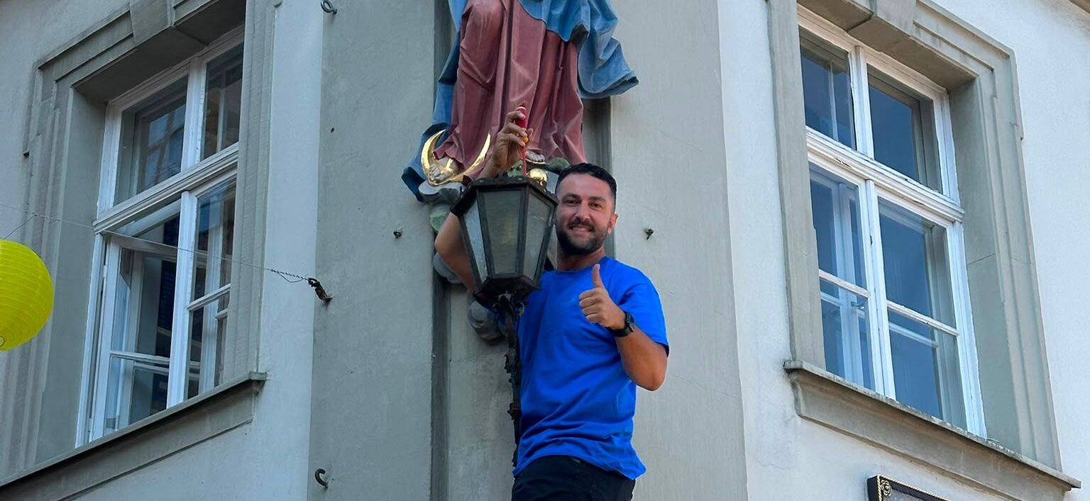 Elektromeister Kemal Marasli mit Daumen hoch vor einer Laterne in der Würzburger Altstadt