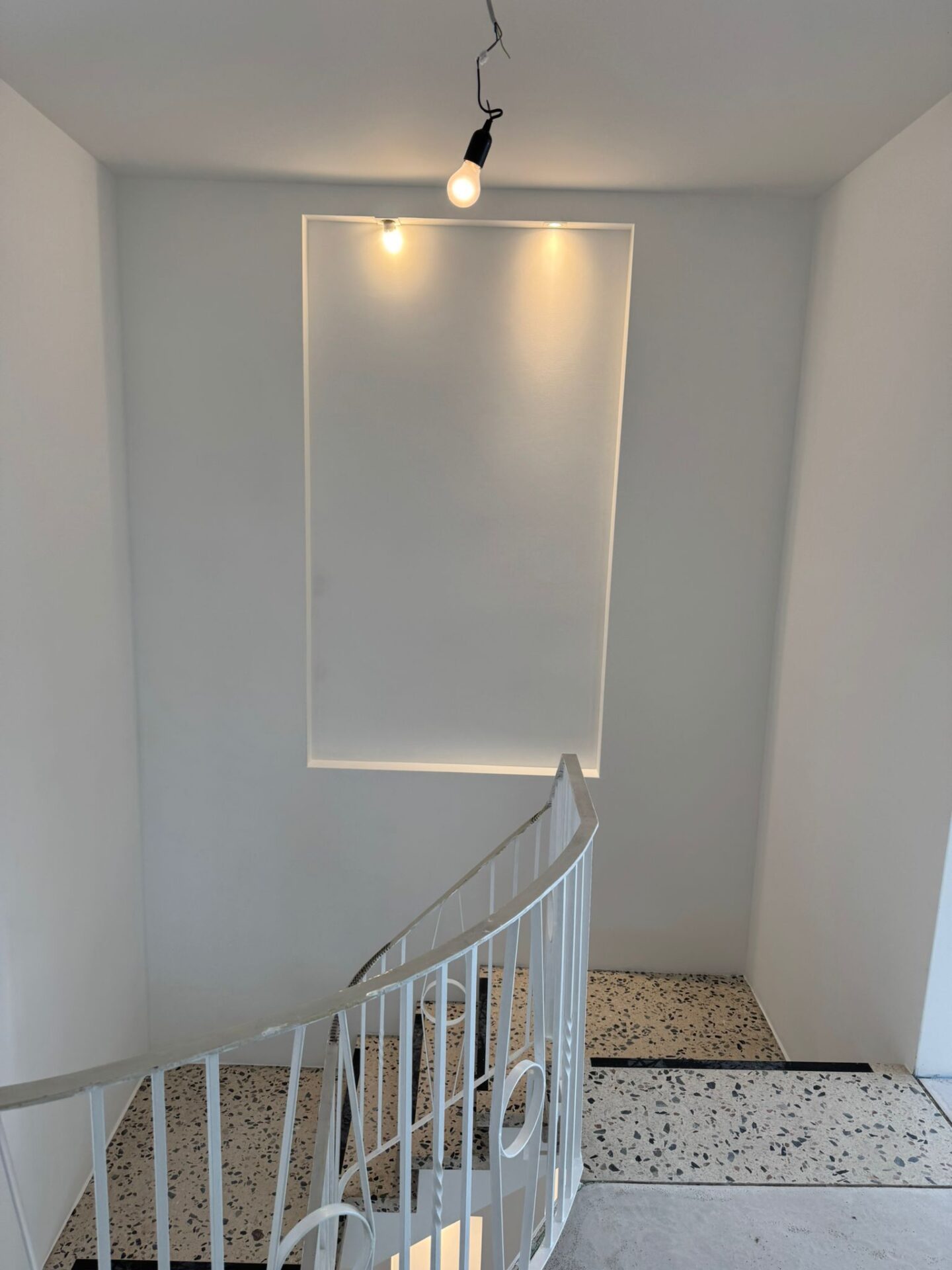 Treppenhaus mit provisorischer Glühbirne und indirekter Wandbeleuchtung