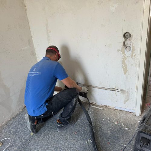 Handwerker arbeitet an elektrischer Installation in Wand