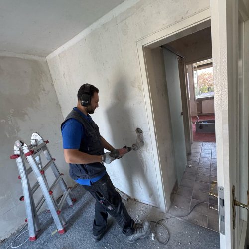 Handwerker bohrt Loch in Wand