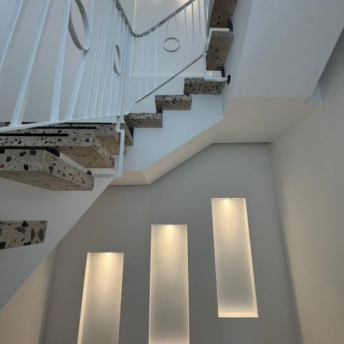 Modernes Treppenhaus mit Terrazzo-Stufen und Beleuchtung.