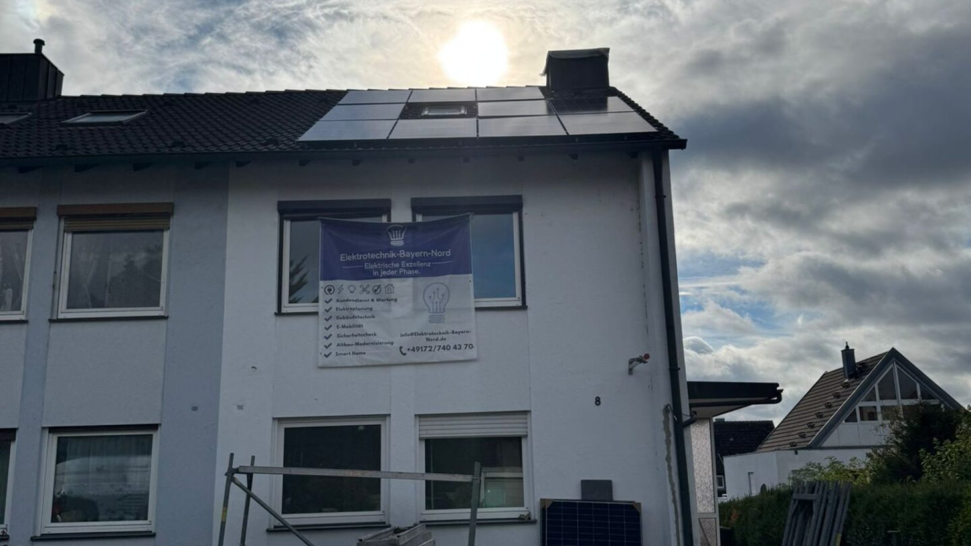 Haus mit Solarpanelen und Baumaterialien im Vordergrund.