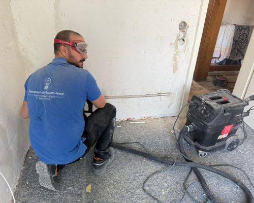 Elektriker arbeitet an Wandinstallation mit Werkzeug.