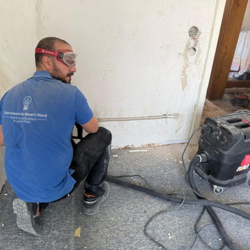 Elektriker arbeitet an Wandinstallation mit Werkzeug.