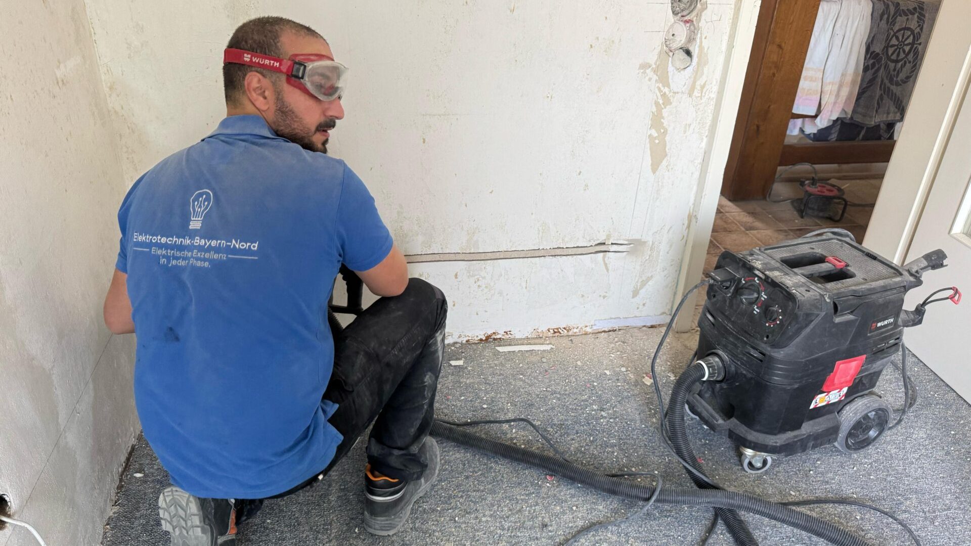 Elektriker arbeitet an Wandinstallation mit Werkzeug.